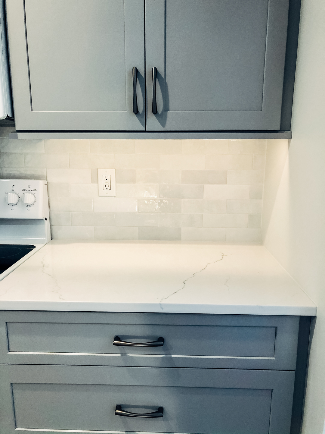 Sleek Grey Cabinetry Over White Tile Backsplash